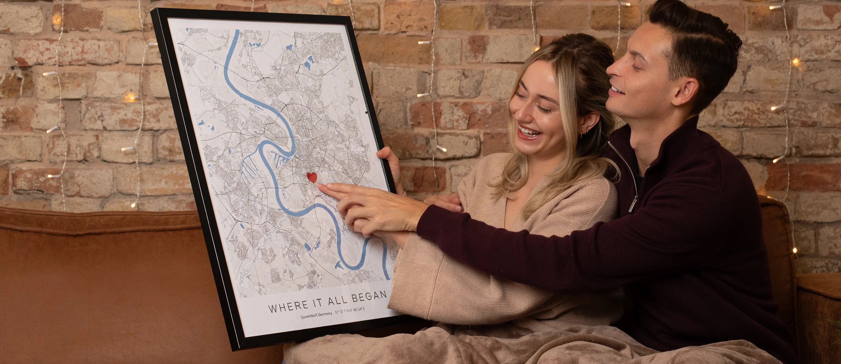 Zwei Personen halten ein gerahmtes personalisiertes Stadtplan-Poster mit Herzmarkierung